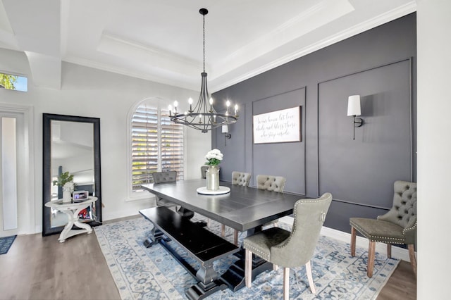 dining space featuring a raised ceiling, crown molding, an inviting chandelier, and hardwood / wood-style flooring