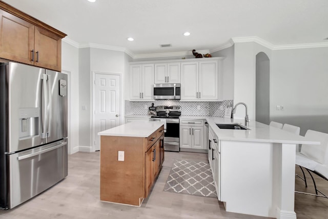 kitchen with a breakfast bar, white cabinets, sink, kitchen peninsula, and stainless steel appliances