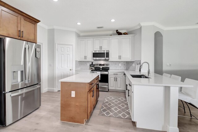 kitchen featuring decorative backsplash, kitchen peninsula, stainless steel appliances, sink, and white cabinets