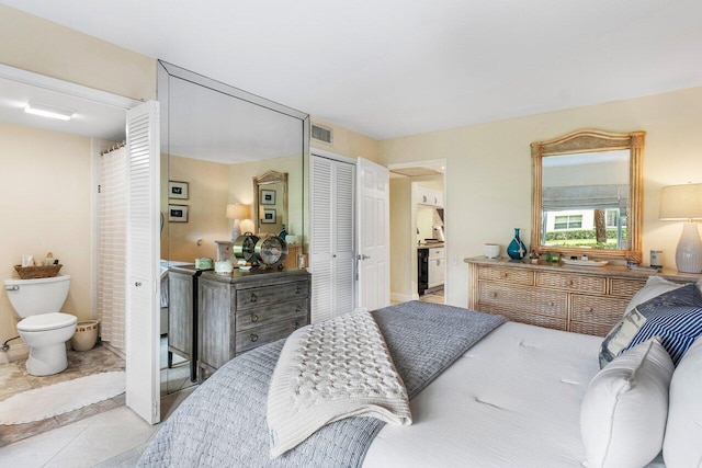 bedroom featuring light tile patterned floors, ensuite bath, and a closet