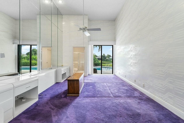 unfurnished bedroom featuring dark colored carpet, a high ceiling, and ceiling fan