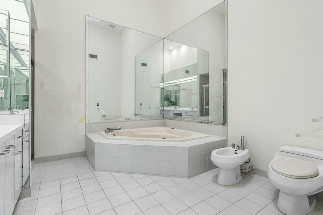 bathroom featuring vanity, a bidet, tile patterned floors, toilet, and tiled tub