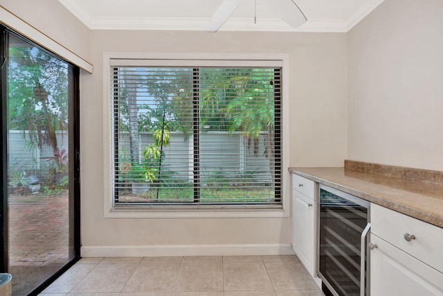 kitchen with light tile patterned floors, white cabinets, beverage cooler, and a healthy amount of sunlight