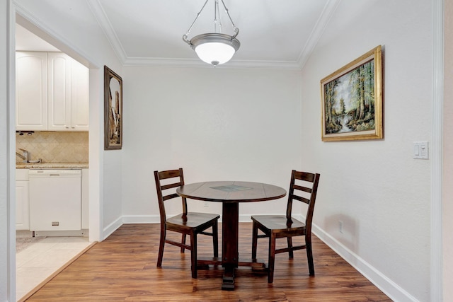 dining area with light wood-type flooring and ornamental molding