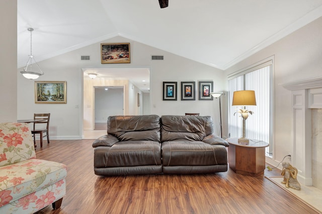 living room featuring hardwood / wood-style flooring, vaulted ceiling, and ornamental molding