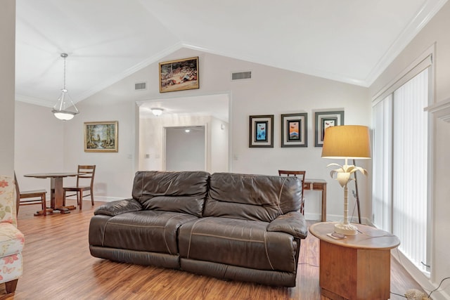 living room featuring vaulted ceiling, a healthy amount of sunlight, ornamental molding, and wood-type flooring