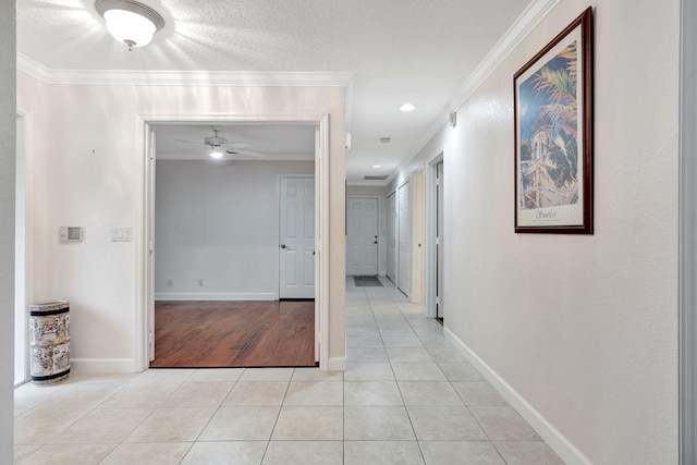 corridor featuring crown molding, a textured ceiling, and light tile patterned floors