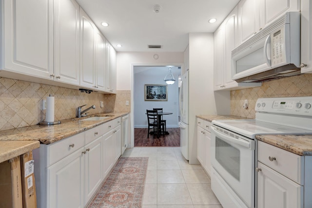 kitchen with light stone countertops, white appliances, white cabinetry, sink, and light tile patterned flooring