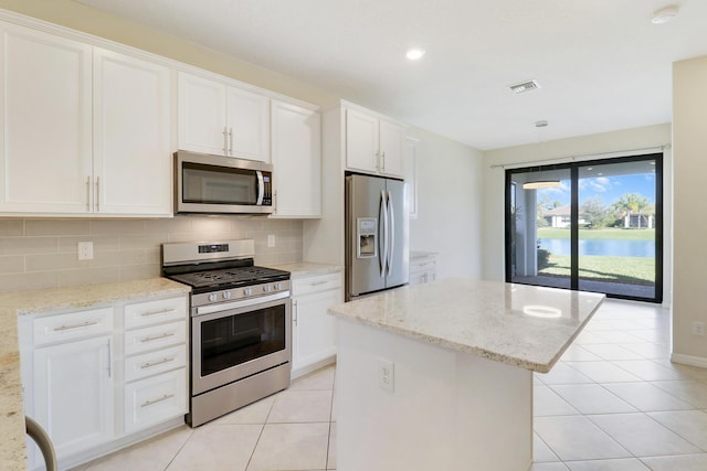 kitchen featuring a center island, light stone countertops, white cabinetry, and stainless steel appliances