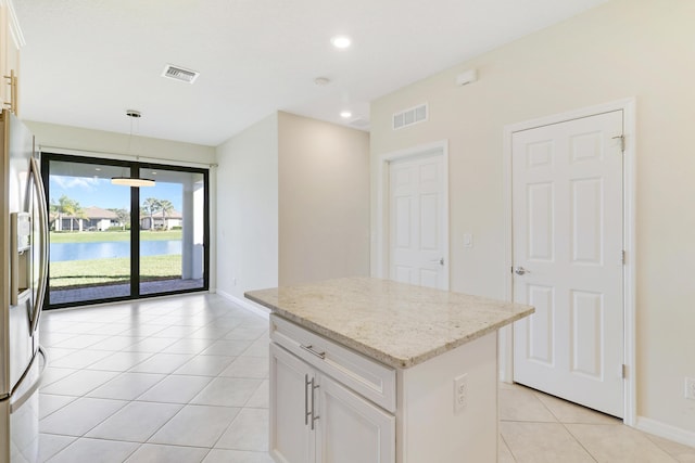 kitchen with pendant lighting, a water view, stainless steel fridge with ice dispenser, a kitchen island, and white cabinetry