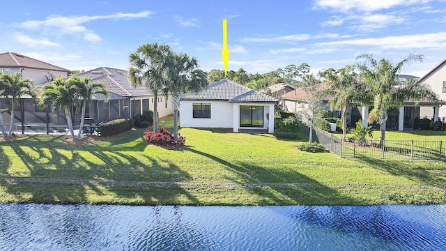 back of property with a yard, a water view, and a fenced in pool