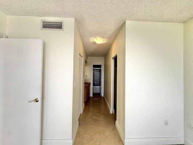 corridor featuring light tile patterned flooring and a textured ceiling