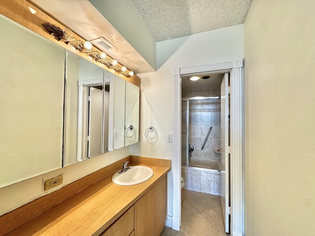 bathroom featuring tile patterned floors, tiled shower / bath combo, a textured ceiling, and vanity