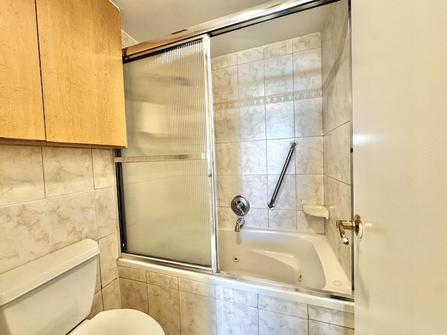 bathroom with toilet, combined bath / shower with glass door, and tile walls