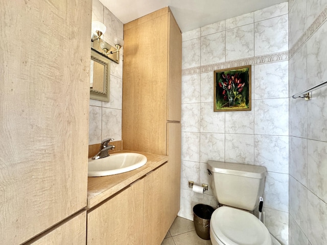 bathroom featuring toilet, tile patterned floors, tile walls, and sink