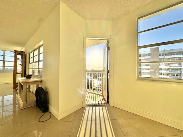 hall featuring light tile patterned floors and a textured ceiling