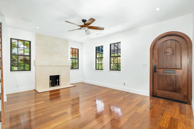 entrance foyer with a tiled fireplace, wood-type flooring, and ceiling fan