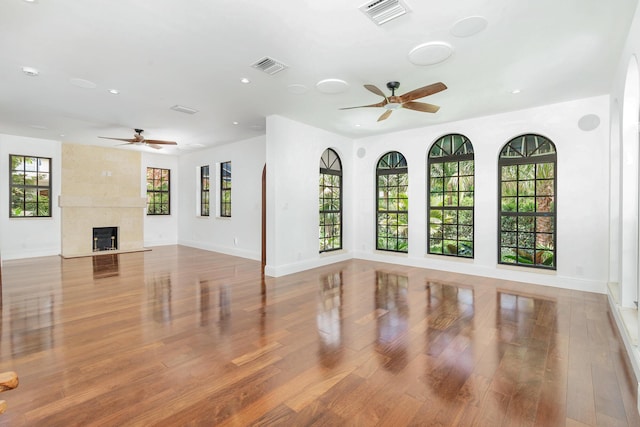 unfurnished living room featuring hardwood / wood-style floors, a premium fireplace, and ceiling fan