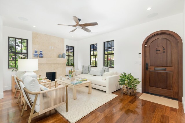 foyer entrance with a tile fireplace, wood-type flooring, and ceiling fan