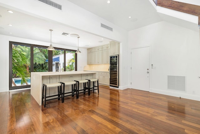 kitchen featuring lofted ceiling, a breakfast bar area, a center island, hanging light fixtures, and cream cabinetry