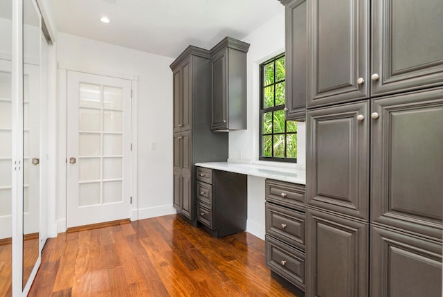 unfurnished office featuring dark hardwood / wood-style flooring and built in desk