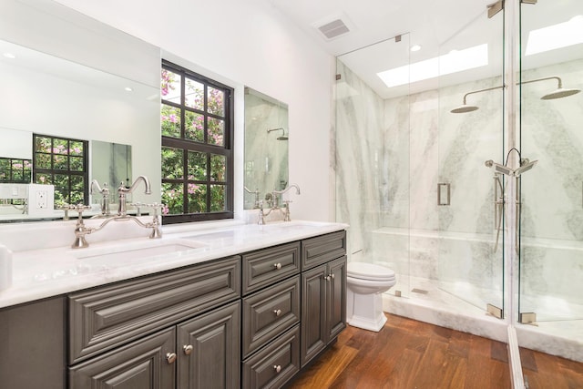 bathroom with vanity, toilet, a shower with shower door, and hardwood / wood-style floors