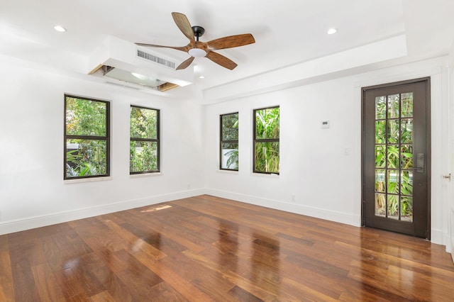 spare room featuring dark hardwood / wood-style floors, ceiling fan, and a tray ceiling