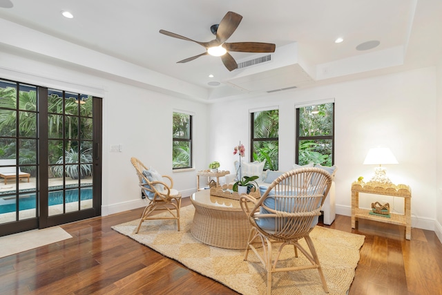 sitting room featuring dark hardwood / wood-style floors, ceiling fan, and a tray ceiling