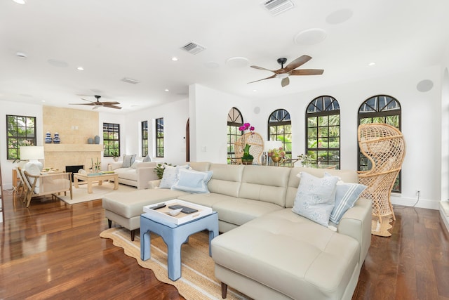 living room featuring a premium fireplace, dark wood-type flooring, and ceiling fan