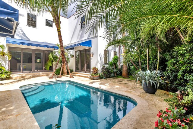 view of swimming pool with a sunroom and a patio