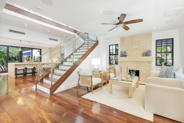 living room with a premium fireplace, wood-type flooring, and a healthy amount of sunlight