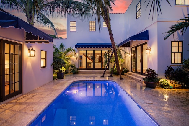 pool at dusk featuring a patio