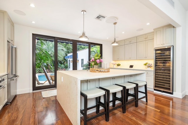 kitchen featuring a kitchen island, stainless steel refrigerator, backsplash, wine cooler, and hanging light fixtures