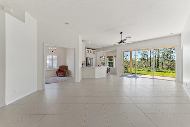 unfurnished living room featuring light tile patterned floors, ceiling fan with notable chandelier, and a textured ceiling