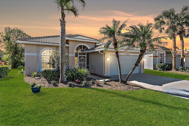 mediterranean / spanish house with a lawn and a garage