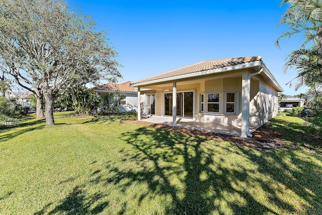 back of property with a lawn, ceiling fan, and a patio area