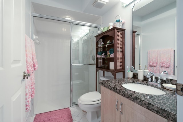 bathroom with tile patterned floors, a shower with door, vanity, and toilet