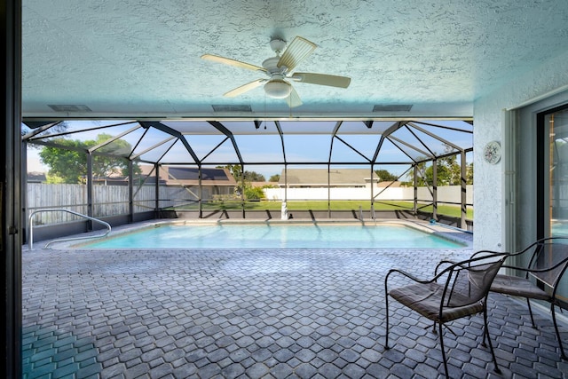 view of pool with glass enclosure, ceiling fan, and a patio