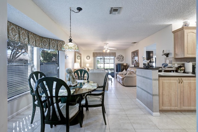 tiled dining area featuring ceiling fan, sink, and a textured ceiling