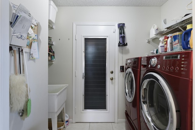 laundry area with a textured ceiling, separate washer and dryer, and light tile patterned flooring