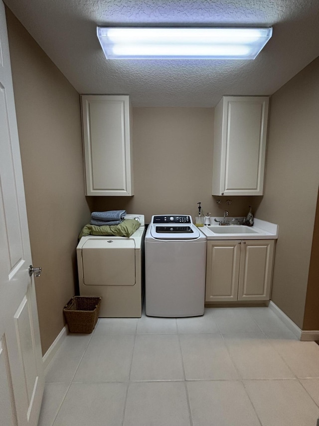 laundry room featuring cabinets, washing machine and dryer, sink, and a textured ceiling