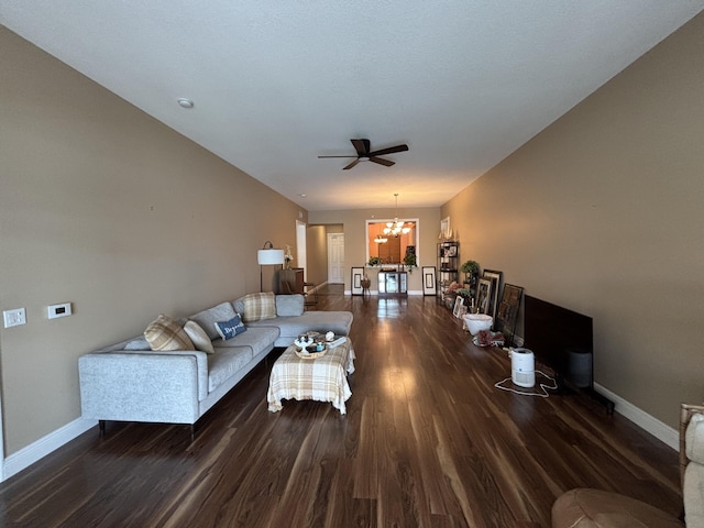 living room with ceiling fan with notable chandelier and dark wood-type flooring