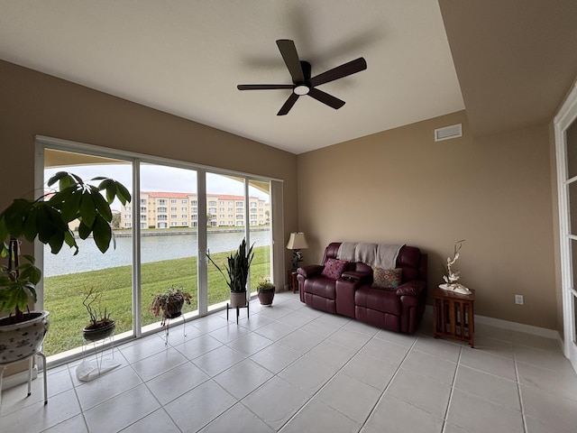 sunroom with ceiling fan and a water view