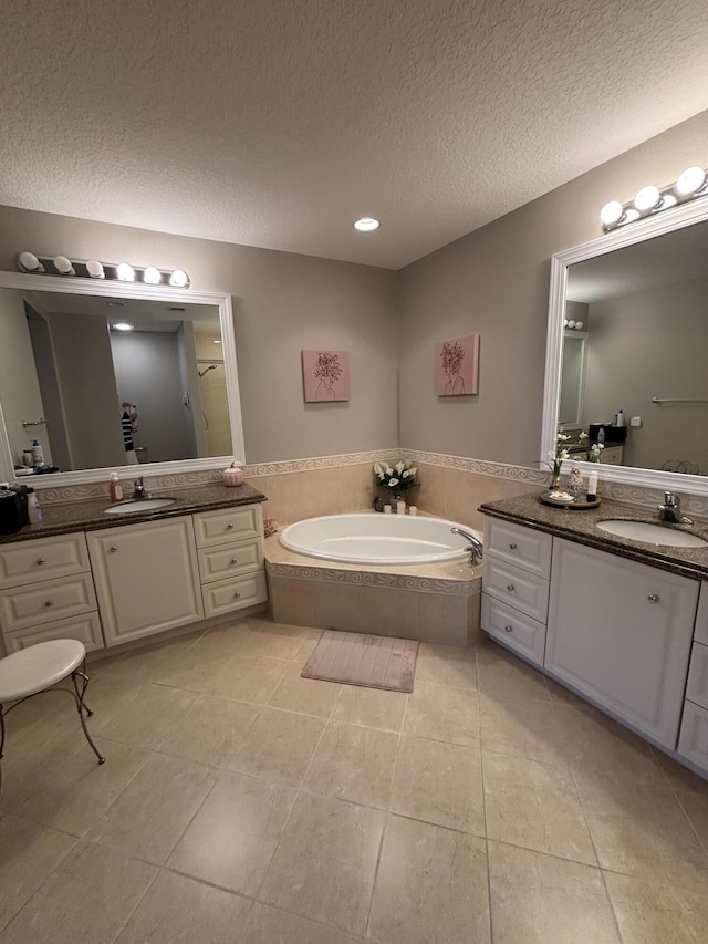 bathroom featuring vanity, a relaxing tiled tub, tile patterned floors, and a textured ceiling