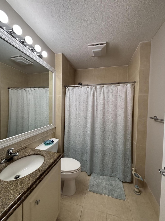 bathroom with tile patterned flooring, vanity, a textured ceiling, and toilet