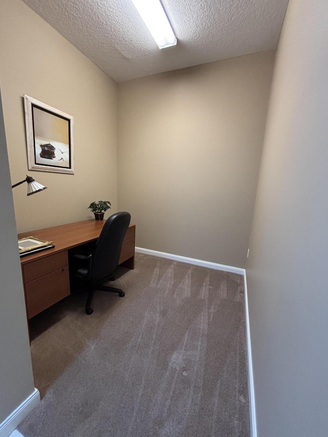 unfurnished office featuring carpet, built in desk, and a textured ceiling