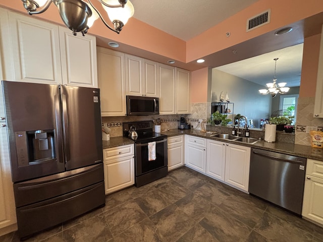 kitchen featuring sink, appliances with stainless steel finishes, white cabinetry, hanging light fixtures, and a notable chandelier