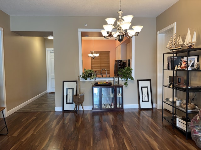 dining room featuring dark wood-type flooring, sink, a textured ceiling, and an inviting chandelier