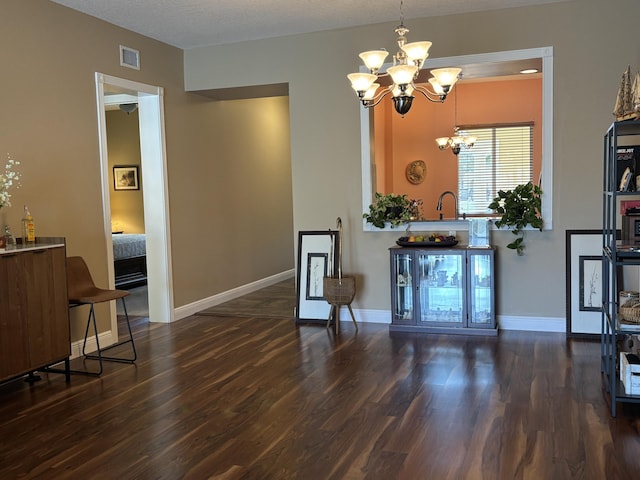 dining area featuring an inviting chandelier, a textured ceiling, and dark hardwood / wood-style flooring