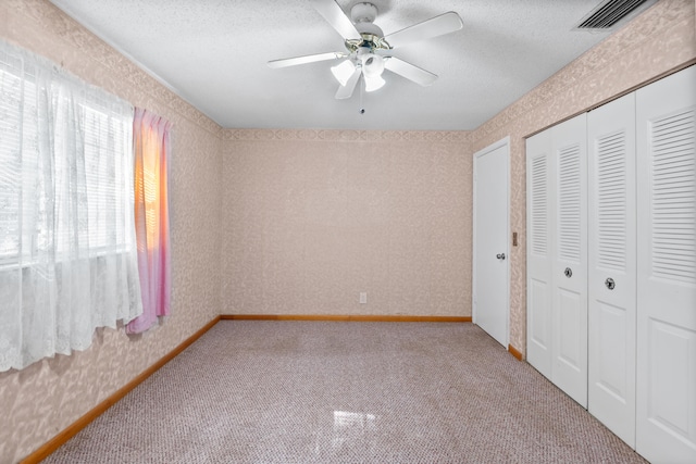 unfurnished bedroom with ceiling fan, a textured ceiling, and light carpet